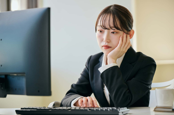 顎関節症になる原因の一つである頬杖をついて仕事をする女性