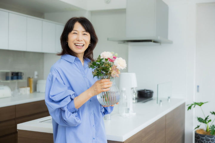歯石を除去して口臭がなくなった女性が笑顔で花をいけているイメージ